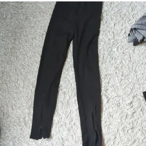 Svarta leggings med dragkedja - Svarta leggings med smal passform och dragkedjor vid bensluten. Perfekta för en clean och stilren look, enkla att matcha med olika outfits. Mjukt och stretchigt material för maximal komfort.