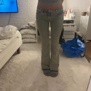 Grå bootcut jeans med låg midja - Säljer ett par grå jeans med snygg tvätt och låg midja. Modellen har bootcut-ben och klassiska fem fickor. Jeansen är i stretchigt denim och har en cool, lite sliten look. Perfekta för dig som gillar en avslappnad men trendig stil.