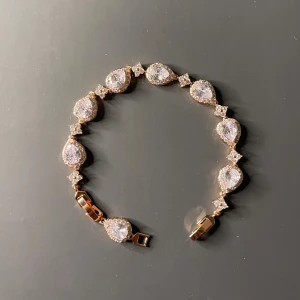 Elegant roséguldfärg armband med glittrande stenar - Vackert armband i roséguldfärg med droppformade, klara stenar. Perfekt till fest eller vardag för en elegant touch.