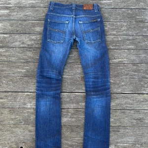 Nudie jeans raw - Vacker fade tack vare högkvalitativ raw denim. Inga större defekter men uppenbart slitet. Små hål i framfickorna, nudie shops reparerar detta gratis. Storlek på etiketten: W29 L32 Modell: thin finn Mått: Midja: 36 cm Ytterbenslängd: 99 cm Benöppning: 15 cm