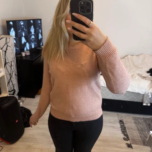 Ljusrosa stickad tröja med rund hals - Superfin ljusrosa stickad tröja med rund halsringning och ribbade muddar vid ärmslut och nederkant. Perfekt för lager-på-lager och passar snyggt till både jeans och kjol. Enkel och stilren design som är lätt att matcha.