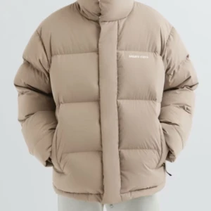 Beige pufferjacka  - Säljer en beige pufferjacka från Axel arigato med hög krage och två stora fickor framtill. Jackan har en boxig, oversized passform och stängs med dragkedja under en bred vindslå. Perfekt för kalla dagar och riktigt snygg till streetwear. 