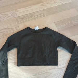 Ribbad croppad långärmad topp Aim'n - Säljer en mörkgrön ribbad croppad långärmad topp från Aim'n då den aldrig kom till användning. Toppen har rund halsringning och är tillverkad i ett stretchigt material. 