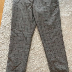 Grå rutiga kostymbyxor - Snygga grå kostymbyxor med klassiskt rutigt mönster. Byxorna har rak passform