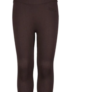 Bruna ribbade leggings från TriDri plus linne  - Mörkbruna leggings från TriDri med ribbad struktur och hög midja. De är tighta och stretchiga, perfekta för träning eller chill. Materialet är mjukt och följsamt, och loggan syns diskret framtill. Snygga att matcha med sporttop eller hoodie. Även linne samma färg märke 