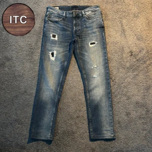 Blå slitna jeans - Snygga blå jeans med slitningar och hål på låren och knäna. Perfekta för en avslappnad och trendig look.