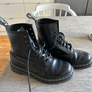 Svarta Dr. Martens boots i skinn - Klassiska svarta Dr. Martens boots. Väldigt lite använda, har en liten repa i skinnet. Strl 37