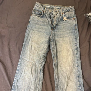 Ljusblå raka highwaist jeans - Säljer ett par ljusblå jeans med klassisk femficksdesign och raka ben. Jeansen har hög midja och är tillverkade i ett robust denimtyg. Perfekta för dig som gillar en avslappnad och tidlös stil.