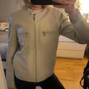 Beige skinnjacka med dragkedjor - Snygg beige skinnjacka i storlek 38 men skulle nog säga den motsvarar mer än 36a om man inte vill ha den alltför tajt. Har några få märken/repor på framsidan och en liten slitning på axeln men inget s syns mycket alls. Kom med pris förlag snälla!🩷