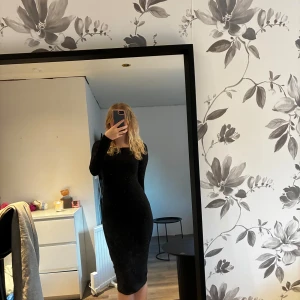 Svart långärmad klänning - En stilren svart långärmad klänning med rund halsringning och figurnära passform. Klänningen är enkel och tidlös, perfekt för dig som gillar minimalistisk stil. Materialet känns mjukt och stretchigt, den går till knäna på mig som är 163☺️