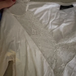 Vit långärmad topp med spets Gina Tricot - Säljer en vit långärmad topp från Gina Tricot i storlek XS. Toppen har en djup v-ringning med bred spetsdetalj framtill som ger en romantisk vibe. Mjuk och tunn bomullskänsla, perfekt att styla med jeans eller kjol.