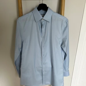 Ljusblå skjorta Charles Tyrwhitt - Snygg ljusblå skjorta från Charles Tyrwhitt i extra slim fit. Skjortan är tillverkad i bomull, har klassisk krage, långa ärmar och knäppning framtill. Perfekt för dig som gillar stilren och clean look.