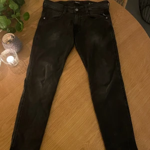 Svarta Replay Anbass jeans, stl 32 - Säljer ett par svarta Replay Anbass jeans i storlek 32. Jeansen har en slim passform med klassisk femficksdesign och snygga detaljer på bakfickorna. Materialet är mjukt och stretchigt jeans, perfekt för en modern look.