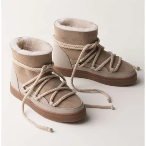 Inuikii skor - Snygga beige moon boots med breda snören och mjukt foder. Skorna har en kombination av mocka och skinn, samt en platt sula i gummi. Perfekta för kalla dagar med sin varma insida och trendiga look. Skorna är endast använda fåtal gånger.