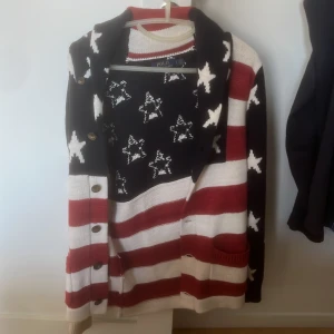USA kofta från Polo Ralph Lauren - Säljer en stickad kofta från Polo Ralph Lauren med amerikansk flaggstil. Koftan har röda och vita ränder, blå partier med vita stjärnor, knappar framtill och två fickor. Perfekt för dig som vill sticka ut med en unik och färgstark look. Nypris: 2599 | mitt pris: 1199 kan gå ner i pris vid snabb affär 