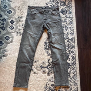 Grå jeans från Jack & Jones, 30/30 - Snygga grå jeans från Jack & Jones i klassisk femficksmodell. Jeansen har en slim passform med normal midja och är tillverkade i mjukt bomullstyg med lite stretch. Perfekta för dig som gillar stilrena och enkla jeans i en neutral färg.