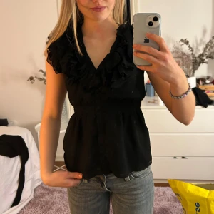 Svart volangblus  - Superfin svart ärmlös blus/topp med volanger och knappar💕säljes då den inte kommer till användning! Passar mig som brukar ha xs/s