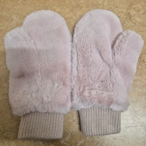 Ljusrosa fluffiga tumvantar Glitter - Supermjuka och fluffiga ljusrosa tumvantar med stickade muddar. Tillverkade i 100% polyester och perfekta för kalla vinterdagar. Köptes och som aldrig användes.