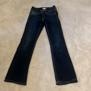 Mörkblå bootcut jeans Gina Tricot - Mörkblå jeans från Gina Tricot Young i storlek 152. Snygg bootcut-modell med kontrastsömmar och klassiska fickor fram och bak. Jeansen har låg midja och är tillverkade i jeansmaterial med en cool tvättad look.