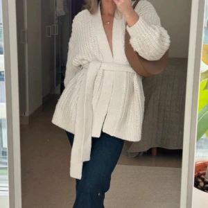 Beige stickad kofta med knytband  - Säljer en chunky beige stickad kofta med breda ärmar och knytband i midjan. H&M. Storlek M