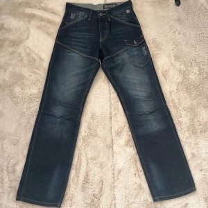 Mörkblå jeans från Voi Jeans, 28R - Snygga mörkblå jeans från Voi Jeans med coola detaljer. De är straight fit med midwaist men kan gå att ha som lowwaist också. Köpta för 800 och endast använda ca 5 ggr