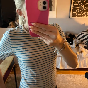 Randig t-shirt i blått och vitt - Säljer en klassisk t-shirt med blå och vita ränder. T-shirten har korta ärmar och rund halsringning. Perfekt för en avslappnad och stilren look. Materialet känns mjukt och skönt mot huden.