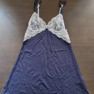 Mörkblå neglige med justerbara band - Söt mörkblå neglige med vita spetsdetaljer över bysten och ryggen. Klänningen har tunna, justerbara axelband. 