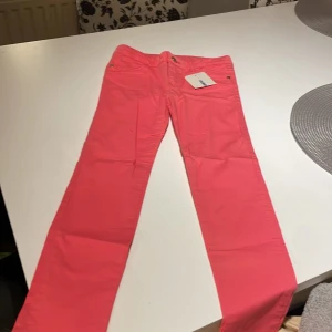 Rosa byxor från LC Waikiki, stl 122-128 - Snygga rosa byxor från LC Waikiki i storlek 122-128 cm. Byxorna har klassisk femficksdesign, raka ben och stängs med knapp och dragkedja. Perfekta för dig som vill sticka ut med färg. Materialet är mjukt och bekvämt, passar till många olika stilar.