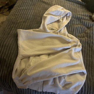 Vit hoodie med dragkedja  - Säljer en vit hoodie med dragkedja framtill och huva. Tröjan har långa ärmar och fickor. Perfekt för chill dagar eller när du vill ha en enkel och clean look.