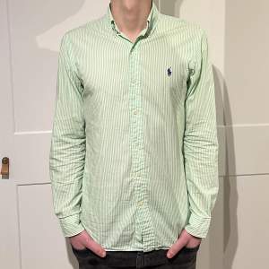 Randig Ralph Lauren skjorta i färgen grön/vit. Inga defekter på skjortan. Size S (slim fit) modellen är 176cm. Hör av dig vid funderingar!