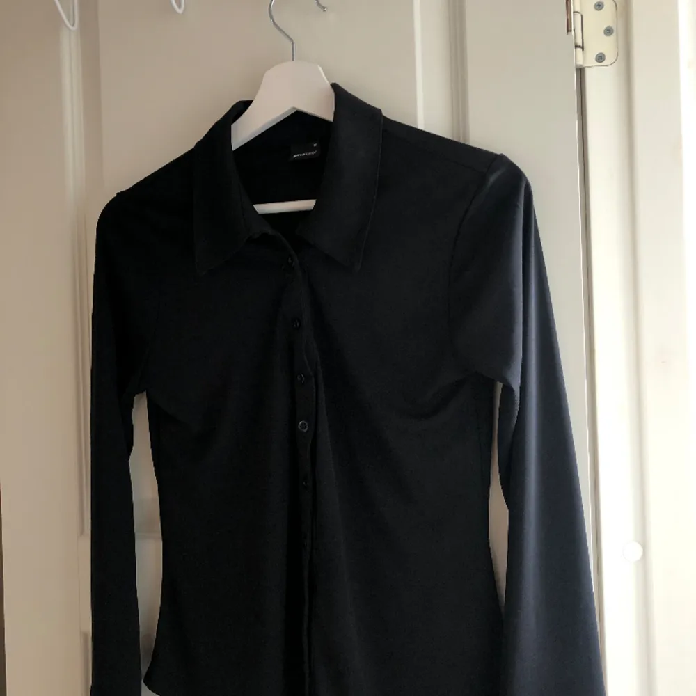 En svart blus som är lite skjortliknande i modellen men har ett väldigt mjukt och skönt material, den är knappt använd!😊🌟. Tröjor & Koftor.