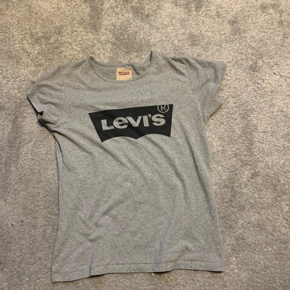 Säljer en grå t-shirt från Levi's i storlek S. Den är i bra skick och har en stor svart Levi's-logga på framsidan. Perfekt för vardagsbruk och passar till det mesta. Skön och mjuk bomullskvalitet. Hör av dig om du är intresserad! 😊. T-shirts.