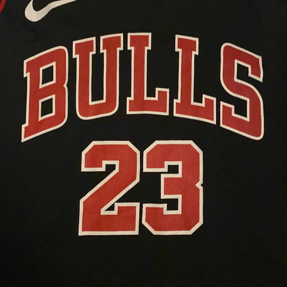 Säljer ett svart Chicago Bulls basketlinne från Nike. Linnet har nummer 23 och namnet Jordan på ryggen. Det är i nyskick och har röda och vita detaljer runt halsen och ärmhålen. Perfekt för basketfans eller som en cool streetwear-stil. Köp direkt eller ge prisförslag 🏀. T-shirts.