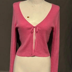 Rosa ribbad kofta från Vero Moda - Säljer en superfin rosa kofta från Vero Moda. Den är ribbad och har en söt knytning framtill. Perfekt för både vardag och fest! Koftan är långärmad och har en v-ringad hals. Den är i storlek L och i mycket bra skick. Passar perfekt till höst och vår.