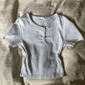 Topp - En T-shirt topp med knappar där uppe. Superfin och enkel. Helt oanvänd.