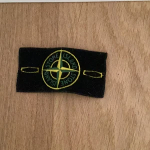 Svart huvudband från Stone Island - Säljer ett svart huvudband från Stone Island. Det är broderat med deras ikoniska logga i gult och grönt. Perfekt för att hålla håret på plats under träning eller andra aktiviteter. Köp direkt eller ge prisförslag 💛