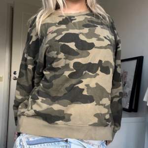 Säljer en cool kamouflagefärgad sweatshirt. Den är perfekt för en avslappnad och bekväm stil. Tröjan har långa ärmar och en normal passform. Den är i bra skick och passar perfekt till jeans eller andra casual outfits. Har ett rosa hjärta där uppe🩷