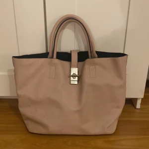 Jättefin rosa väska - Ser beige ut i bilden men är ljusrosa. Har mycket plats. Använde den hela nian och fick plats med alla skolböcker och dator. Silverknappar längst ner som skyddar lädret från marken. Säljs inte längre. Lite smutsig men gåt bort med vatten.Köpt för 600