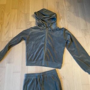 Grå hoodie och byxor från Giantoot - Säljer en supermysig grå hoodie och matchande byxor från Giantoot. Hoodien har dragkedja och långa ärmar, perfekt för en chill dag hemma eller en promenad ute. Byxorna har en bekväm resår i midjan med dragsko för bästa passform. Setet är gjort i mjukt och skönt material, perfekt för höst och vinter. Köp nu och håll dig varm och snygg! 💛