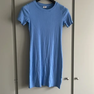 Blå kortärmad klänning - Säljer en superfin blå klänning med korta ärmar. Den är enkel och stilren, perfekt för både vardag och fest. Klänningen är i ett mjukt och bekvämt material som känns skönt mot huden. Passar perfekt till sommaren!