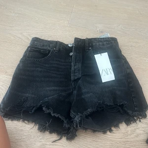 Svarta jeansshorts från Zara - Säljer ett par svarta jeansshorts från Zara i storlek S. De har en cool fransig kant och en hög midja. Perfekta för sommaren eller en avslappnad fest. Shortsen är i nyskick och har aldrig använts. Passar perfekt till en t-shirt eller en snygg topp!