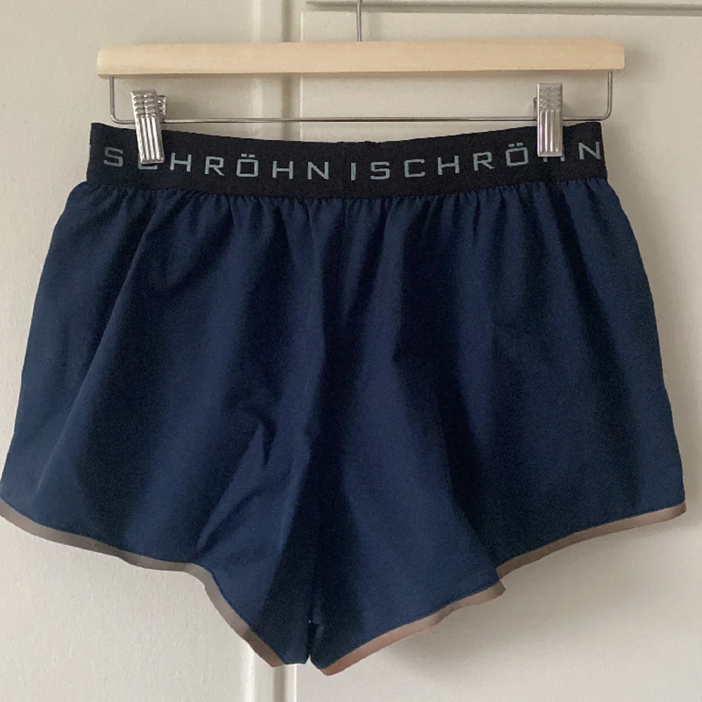 Snygga röhnisch shorts. De är marinblå i färgen och på resåren i midjan står det röhnisch med ljusblått. Har även en reflexkant längst ner på benet så man syns bra i mörkret. Sitter superskönt och passar sig bra till våren och sommarens alla löpturer. Shorts.