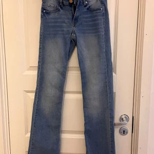 Jeans i två färger - Två par jeans i olika färger. Ett par är ljusblåa och det andra paret är svarta. Båda paren har en klassisk femficksdesign och raka ben.