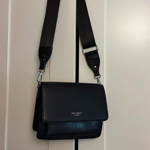 Axelväska  - En svart fin väska i konst läder med ett stort fack och ett litet, väskan är knappt använd! 