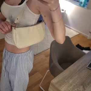 Väska  - En söt liten väska som man kan ta med sig när man går ut. I denna väska får man plats med: mobilen, liten pefym, plånbok, nyckar och smink samtidigt. En väldigt smidig väska. Den e gulvit som ni ser så inte 100% vit om man jämnför med mitt linne. 