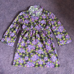 Barn klänning  -  Lila, blå, grön och rosa  barn klänning med blommor och krage i nacken,  i bra skick. I barn storlek.   Denna är inte sydd av oss!