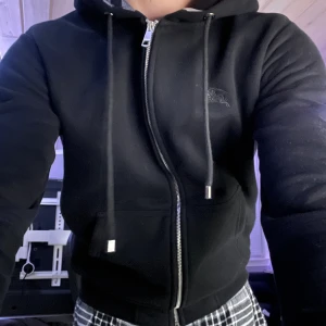 Burberry Hoodie Svart - Säljer min svarta Burberry hoodie, inte så mycke mer än de! Använder den knappt så därför säljer ja den. Den är fett skön o go på sommarkvällen o när det blåser ute. Riktigt skön hoodie samt snygg. Jag är 179 Väger 70kg Den är Storlek S   