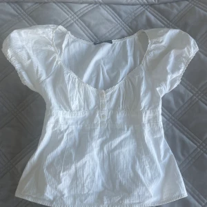 brandy melville blus - Säljer denna super söta vita blusen från brandy! Perfekt nu till sommaren🌸🤍köpt på deras egna butik. 
