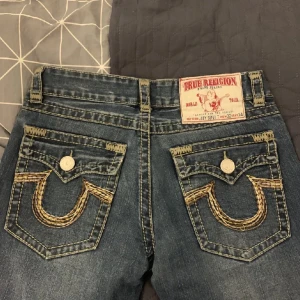 True religion jeans - Säljer dessa då de ej kommer till användning. Storlek 32/34 och midjemåttet tvärs över är ca 42cm, innerbenslängd ca 70cm. Bilderna är från förra ägaren. Bra skick, är dock lite slitna vid benslutet.