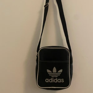 Adidas - Axelremsväska - Säljer en nyinköpt adidas väska i utmärkt skick!  Färg: Svart Material: Läder